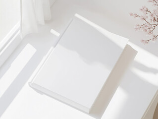 Minimalist white book on a bright surface with soft natural light, blank cover design concept for branding, mockup, or editorial layout in a peaceful setting