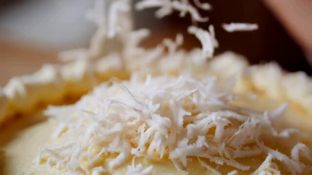 Close-Up in Slow Motion of Shredded Coconut Cascading onto a Cake &ndash; A visually rich scene where delicate, snowy coconut flakes contrast against smooth, creamy frosting for a delectable dessert reveal.