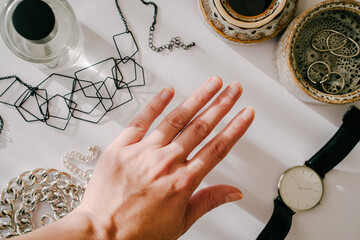 Woman fashion feminine composition. Woman's hand picking up accessories: rings, chain, bracelet on...