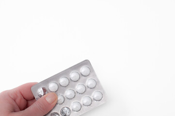blister with pills held in hand on white background