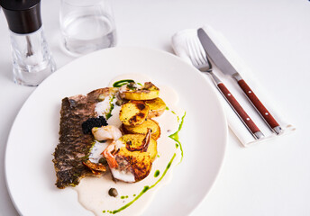 A beautifully presented seafood dish featuring grilled fish, succulent shrimp, and perfectly roasted potatoes drizzled with a vibrant sauce. This culinary masterpiece highlights fine dining