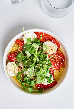 This vibrant salad includes slices of ripe tomatoes and creamy mozzarella cheese topped with fresh arugula and a flavorful dressing. Perfect for a light meal or appetizer