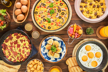 A variety of delicious Middle Eastern egg dishes. Served with fresh orange juice, bread, green salad, pickles and potato cubes. Top view with close up.