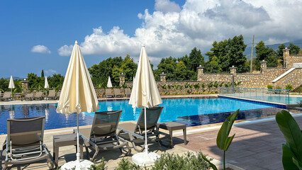 A Luxury Poolside With Sun Loungers And White Umbrellas Under A Clear Blue Sky In Alanya, Turkey,...