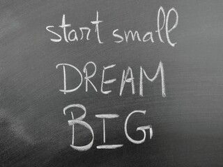 Motivational phrase 'Start Small, Dream Big' hand-written in chalk on a blackboard background