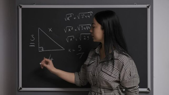 The teacher writes various mathematical formulas on a blackboard and gives the lesson. Teacher writes on blackboard.