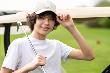 Waist up of a young golfer in cap with a brassie in hand