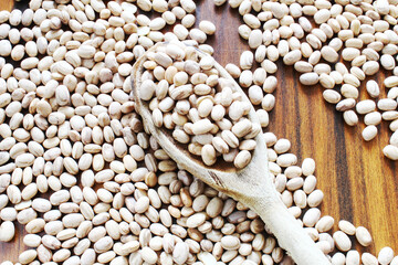Obraz premium Carioca beans in a wooden spoon on the rustic table. Brazilian seeds.