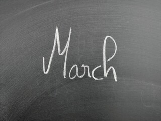 Handwritten word 'March' on a chalkboard surface conveying education, creativity, and handwriting...