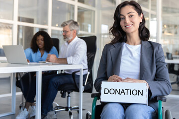 Disabled female worker doing her job in office environment holding box with donation inscription