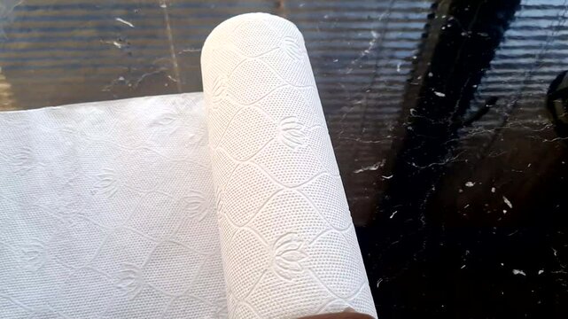 a roll of white kitchen paper unfolds on the table