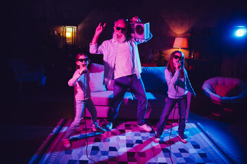Grandfather and granddaughters singing and enjoying a fun karaoke night in the living room