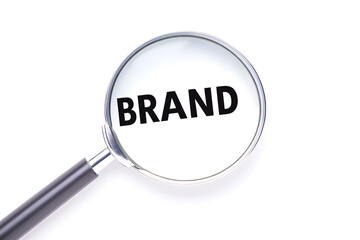 A magnifying glass focuses on the word 'BRAND', highlighting the importance of brand identity and recognition in business and marketing.