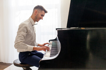 young guy in white shirt plays on old black piano, musician pianist performs melody on acoustic musical instrument © Богдан Маліцький