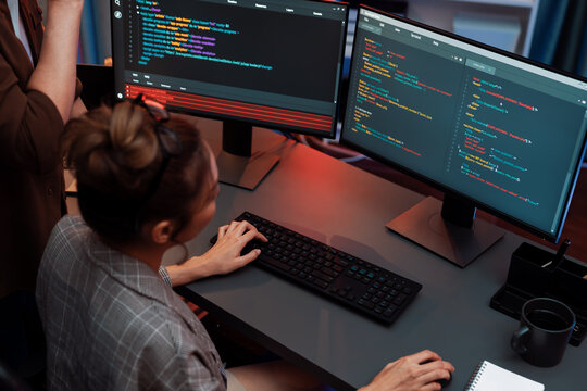 IT developers discussing with point to intelligent website development coder system running data online on pc of two screens with information technology at neon light room at modern office. Infobahn.