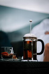 Woman in white robe enjoys tea on terrace with snow-capped mountains in the background during a serene afternoon