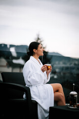 Woman enjoys tea on a terrace overlooking snow-capped mountains during a serene moment