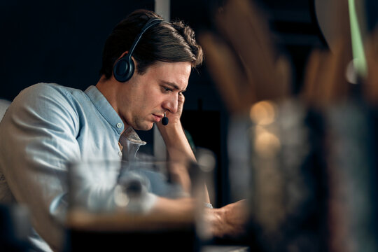 Call center consulting with customers on headphones on monitor in business paragraph with typing on pc with dynamic data marketing analysis planning at modern home office at night time. Pecuniary.