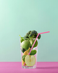 Vibrant glass filled with greens, apple, broccoli, spinach, cucumber, and banana, adorned with pink...