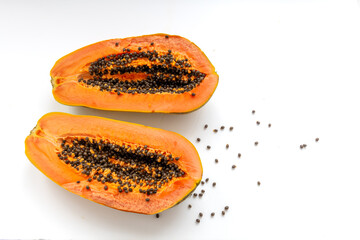 Flat lay of two halves of a ripe papaya exposing the sweet tasty orange colour flesh and black...