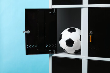 Open locker with soccer ball on light blue background