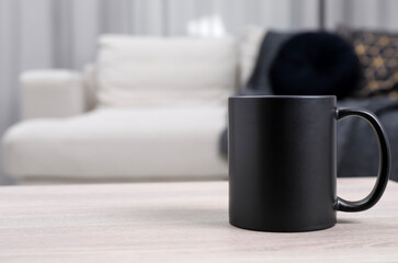 One blank black ceramic mug on white wooden table. Mockup for design