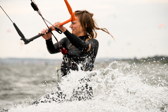 Close-up photo of a female kite surfer holding the handle of a kite with her hands