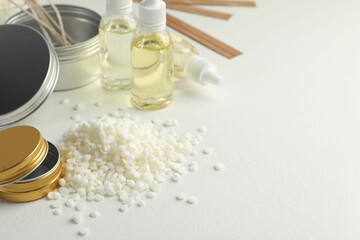 Soy wax and other supplies for making candles on white table. Space for text