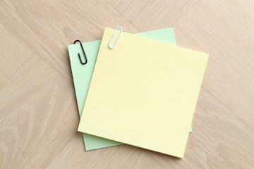 Paper notes with clips on wooden table, top view. Space for text