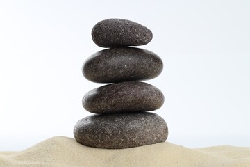 Stack of rocks on sand against white background. Harmony and life balance