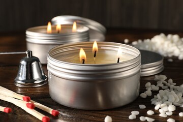 Burning soy wax candles, matches and snuffer on wooden table, closeup