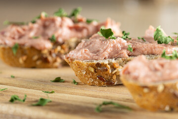 Slices of spreadable pâté made with red onion and butter on rustic bread on wooden cutting board. Close up view.