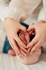 A close up of parents hands forming a heart around their newborns tiny feet, symbolizing love,...