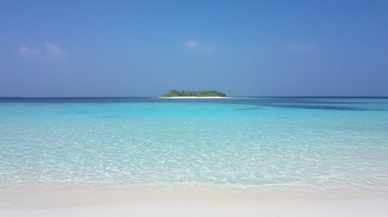 Obraz premium A tranquil island in a vast ocean under a clear blue sky showcasing a serene tropical paradise
