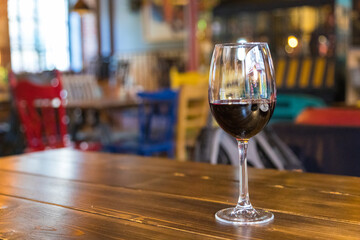 A glass of red wine on a wooden table.