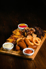 Assorted grilled meat appetizers on wooden board, top view.
