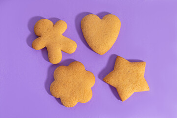 Homemade gingerbreads or cookies on purple background. Gingerbread cookies of different shapes