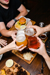 Friends toasting with beer over dinner table.