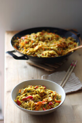 Bowl of stir fry vegetables and noodles, served on the table. Selective focus.