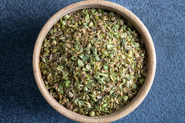 A bowl full of dried and ground natural mountain thyme on gray background.