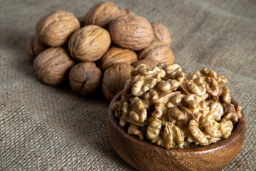 Peel walnuts and whole walnuts in wooden bowl,closeup 