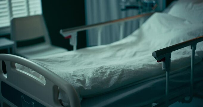 Empty hospital bed with neatly arranged sheets and pillow.