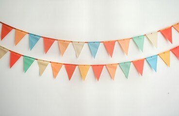 Obraz premium Colorful triangular flags create festive garland on white wall. Double row of hanging bunting adds cheerful vibe. Pastel colors evoke celebration. Decorations ideal for parties, birthdays, events.