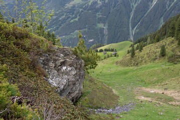 Rocky Outcrop Overlooking Lush Alpine Valley with Wooden Huts in Zillertal, Tirol, Austria