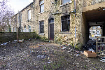 Photo taken of an extremely run down property that has had a massive fire showing the outside of the property that is in need of repair and the neglected front garden of the house