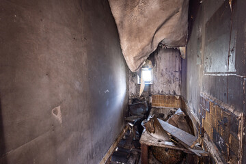 Photo of an extremely run down property that has had a massive fire showing the burnt walls floor and ceiling in the bathroom and the charded bathroom in the fire damaged house