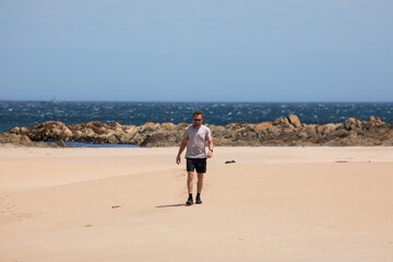 caucasian man walking beach sun blue sky travel