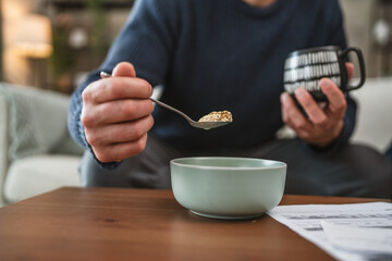 close up on male hand hold full spoon and mug