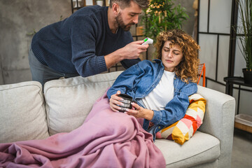 Naklejka premium A man measures a woman temperature with a digital infrared thermometer