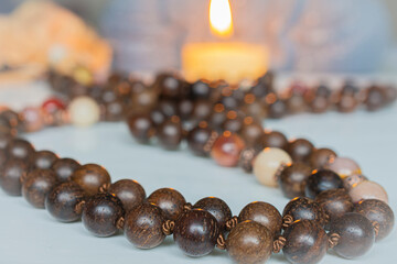 Close-up of wooden mala prayer beads laid out on a surface, featuring smooth, round beads with a natural brown finish. Creating a very peaceful and meditative setting.